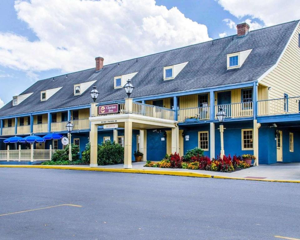 a large blue inn with flowers in front of it at Clarion Inn Strasburg - Lancaster in Strasburg