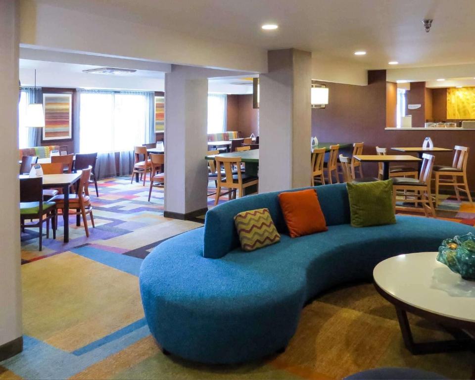 a living room with a blue couch and tables and chairs at Quality Inn Cranberry Township in Cranberry Township