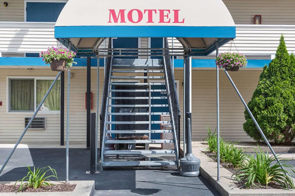 a motel sign with a staircase in front of a building at Rodeway Inn Milford - I-84 in Milford