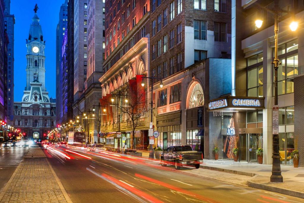 uma movimentada rua da cidade à noite com uma torre do relógio em Cambria Hotel Philadelphia Downtown Center City em Filadélfia