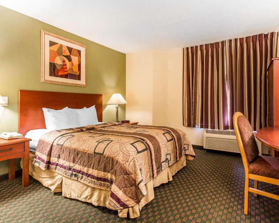 Habitación de hotel con cama, escritorio y mesa. en Sleep Inn Near Ft Jackson, en Columbia