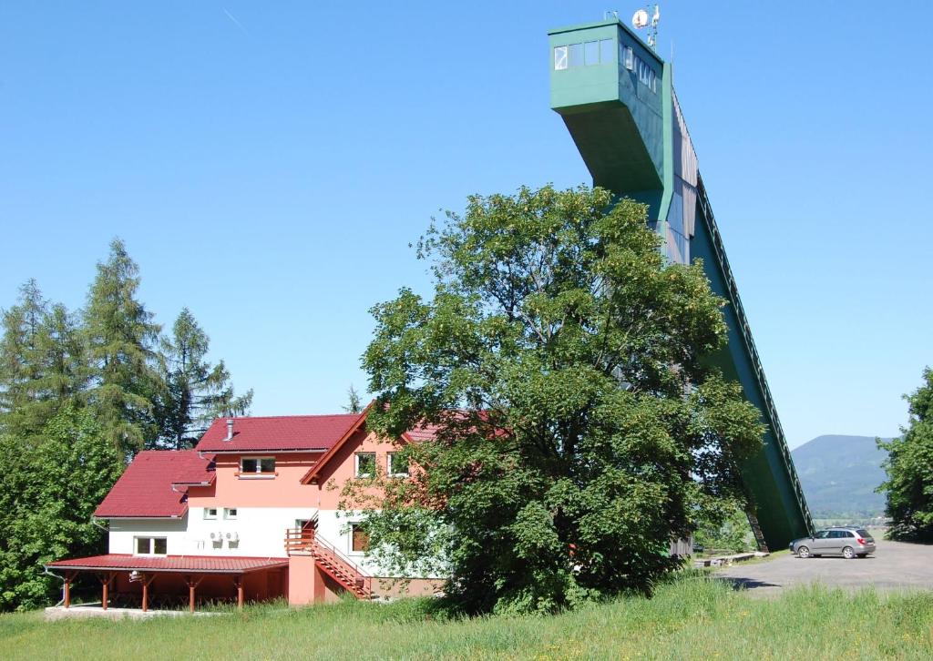 ein Gebäude mit einem Turm neben einem Baum in der Unterkunft Penzion u můstku Jiřího Rašky in Trojanovice