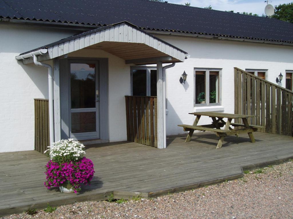 a wooden deck with a picnic table and flowers at Brattenstrand Holiday Apartments in Jerup
