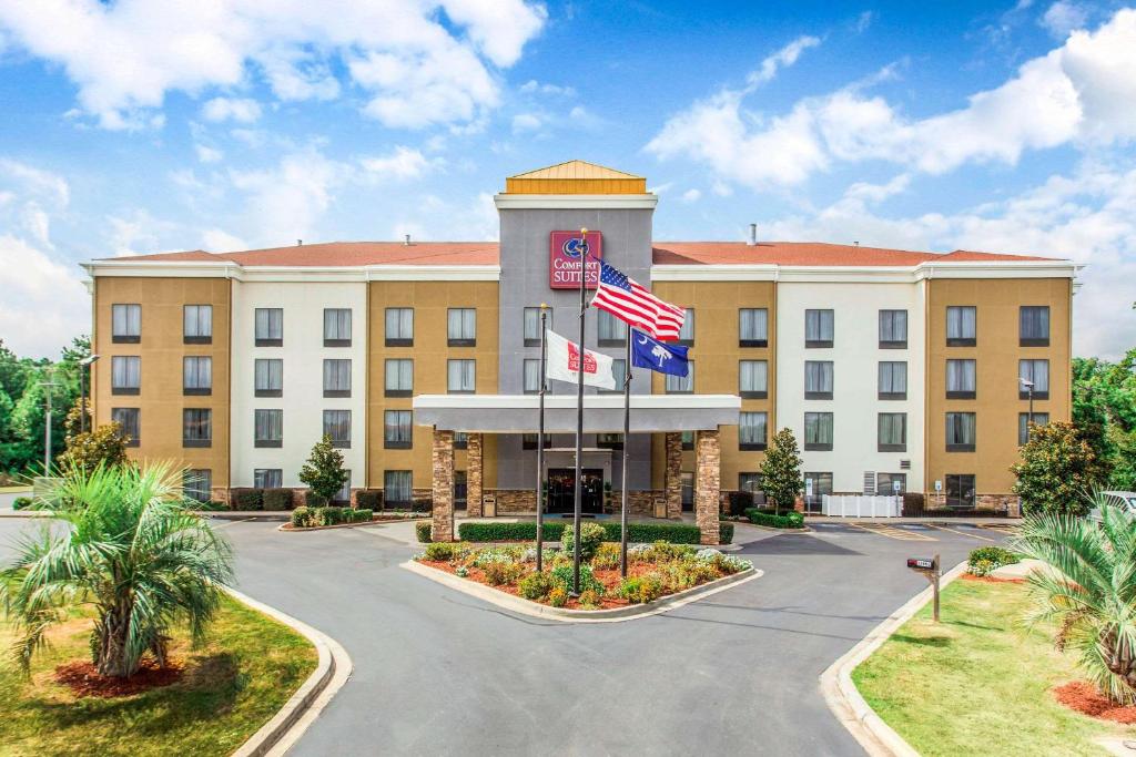 un hôtel avec deux drapeaux devant un bâtiment dans l'établissement Comfort Suites Clinton near Presbyterian College, à Clinton