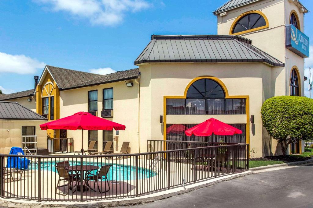 a building with tables and red umbrellas in front of it at Quality Inn at the Park in Fort Mill