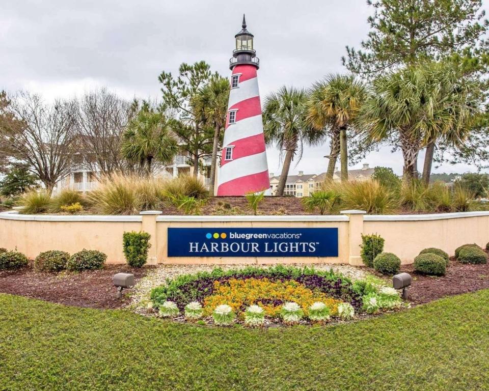 a lighthouse with a sign in front of a garden at Bluegreen Vacations Harbour Lights in Myrtle Beach