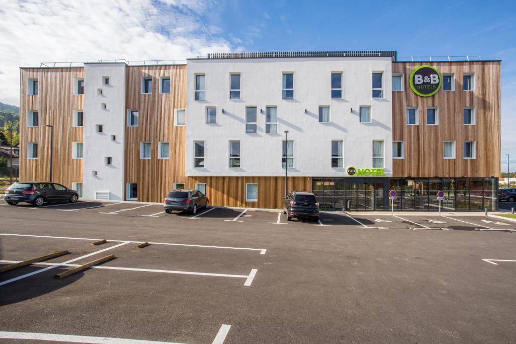 un parking en face d'un grand bâtiment dans l'établissement B&B HOTEL ANNEMASSE Saint-Cergues, à Saint-Cergues