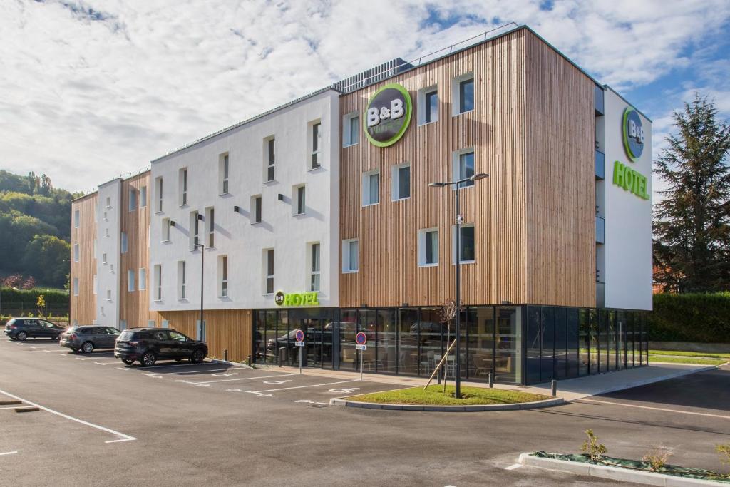 a large building with a car parked in a parking lot at B&B HOTEL ANNEMASSE Saint-Cergues in Saint-Cergues