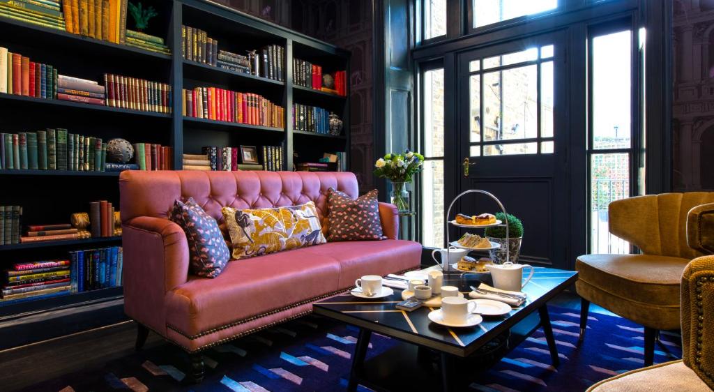 ein Wohnzimmer mit einem rosa Sofa und einem Tisch in der Unterkunft The Academy - Small Luxury Hotels of the World in London