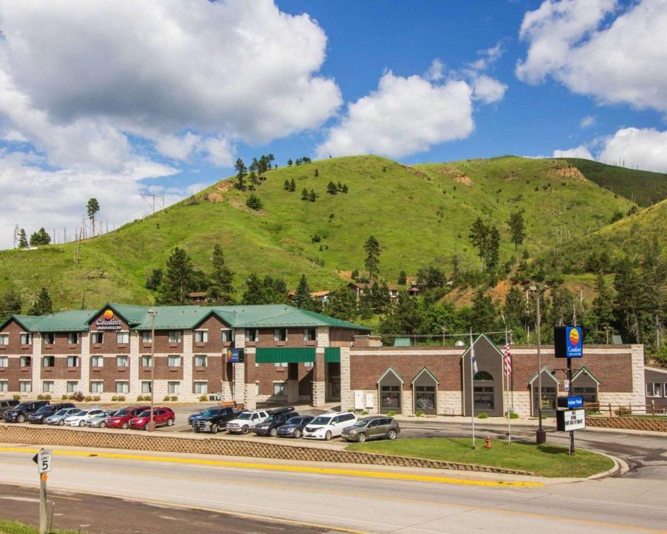 um edifício com carros estacionados em frente a uma montanha em Comfort Inn & Suites Hotel in the Black Hills em Deadwood