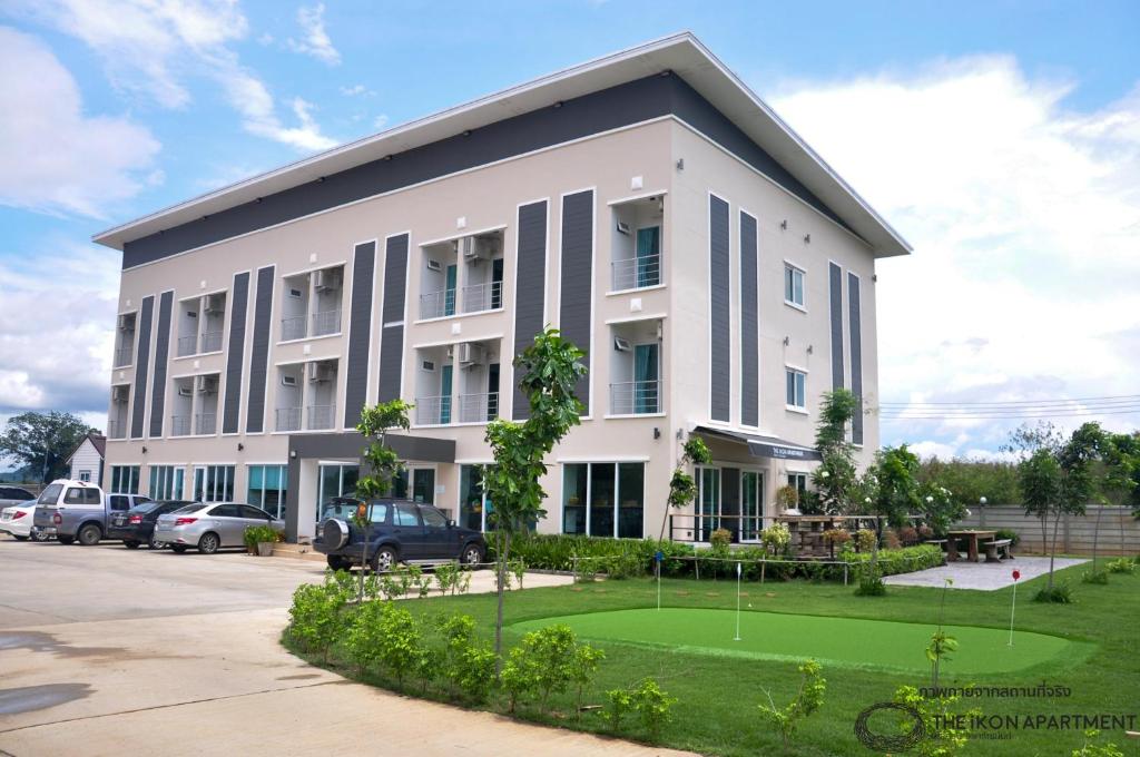 a large white building with a green lawn in front at The iKon Apartment in Ban Nong Pho