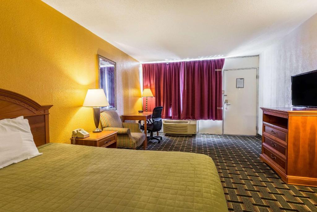 a hotel room with a bed and a desk and a television at Rodeway Inn Denmark-Jackson in Denmark