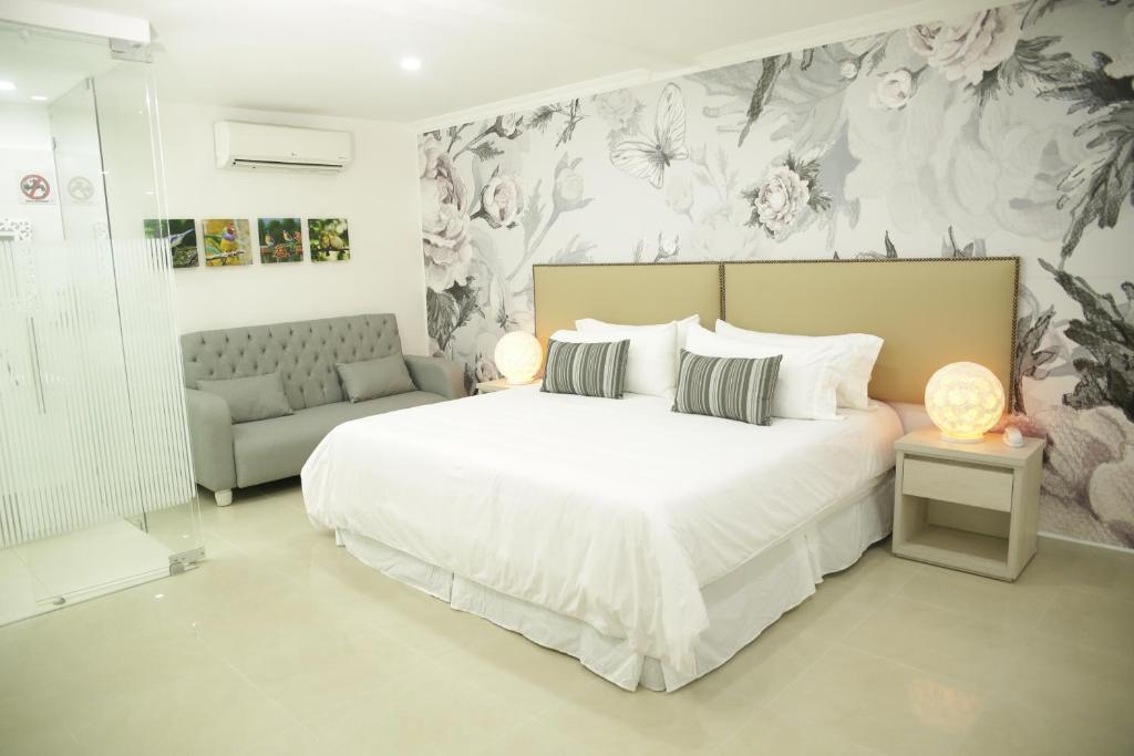 a bedroom with a large white bed and a couch at HOTEL HABANA REAL in Apartadó