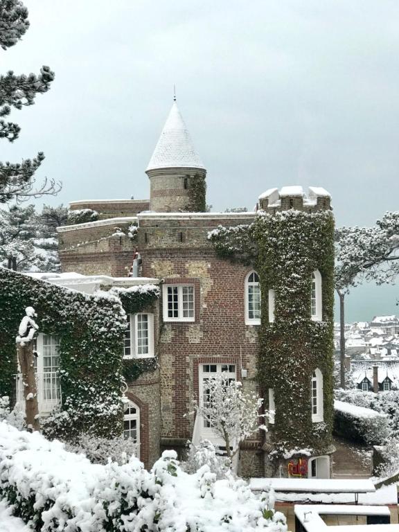 a building covered in ivy in the snow at Domaine Saint Clair - Le Donjon in Étretat