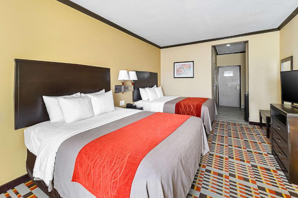 a hotel room with two beds and a flat screen tv at Quality Inn & Suites in Lubbock