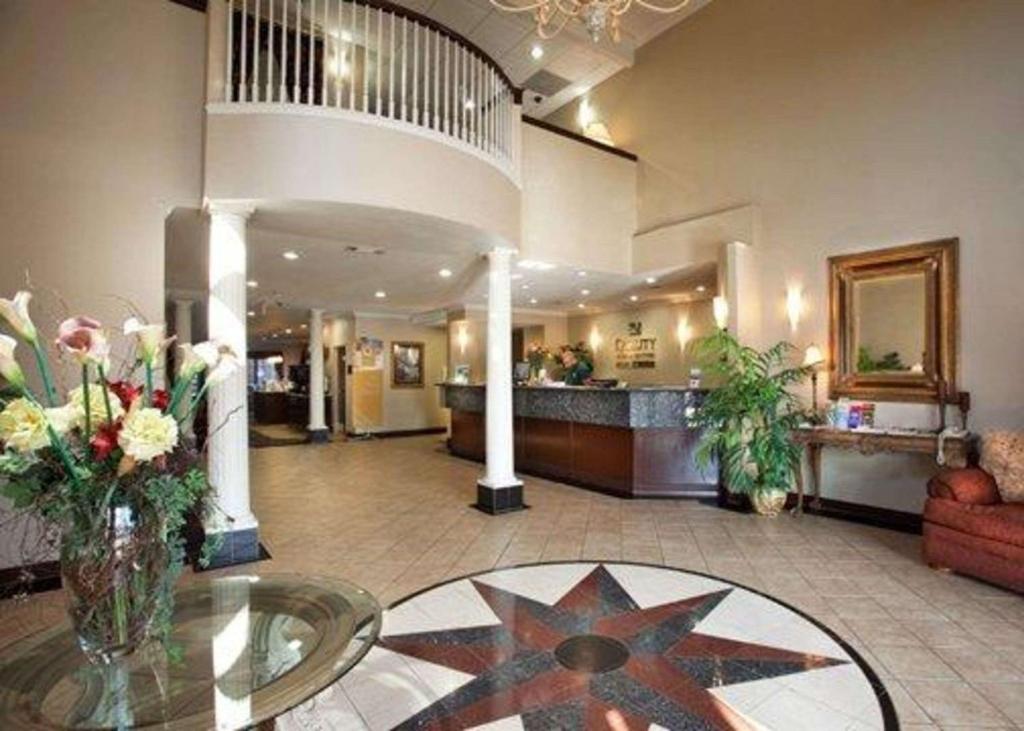 un vestíbulo con un jarrón de flores sobre una mesa de cristal en Quality Inn & Suites Near University, en Waco