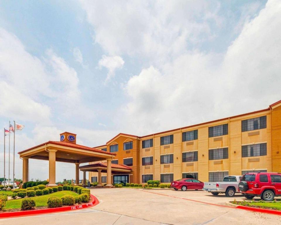 a large yellow building with a parking lot at Comfort Suites Lake Ray Hubbard in Rowlett