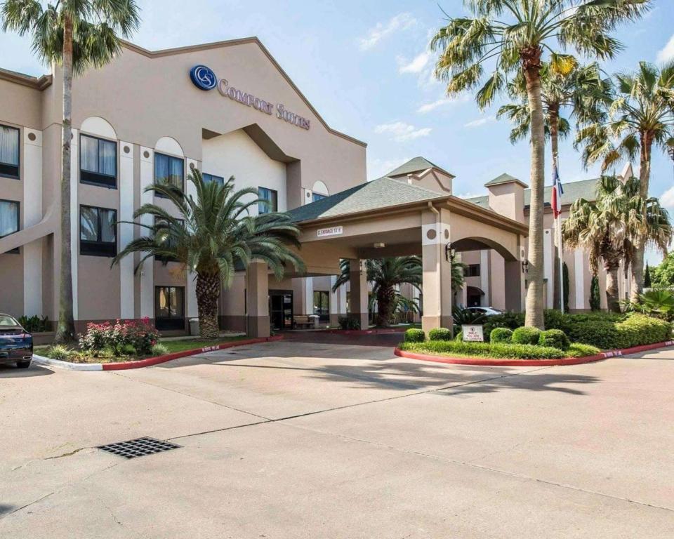 a hotel with palm trees in front of it at Comfort Suites Stafford Near Sugarland in Stafford