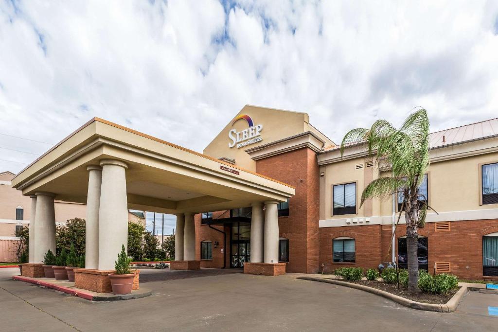 a hotel front of a building with a palm tree at Sleep Inn & Suites Stafford in Stafford