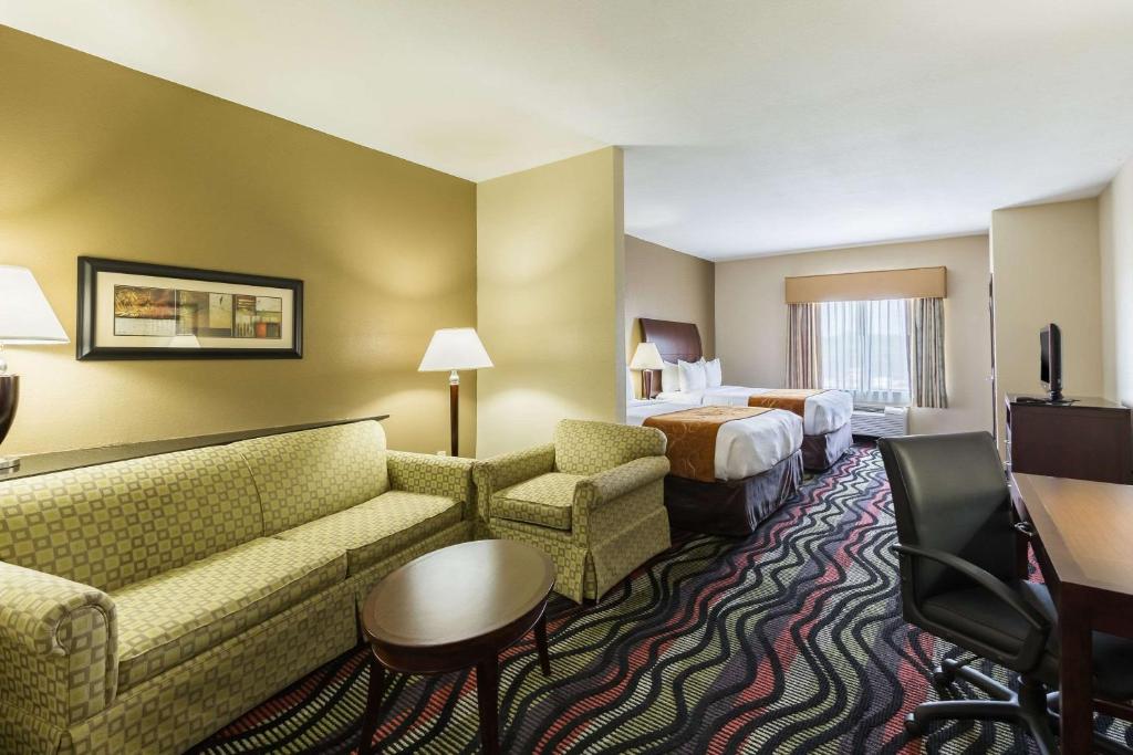 a hotel room with a couch and two beds at Comfort Suites Beaumont I-10 in Beaumont