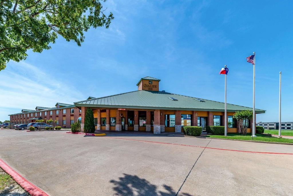 um grande edifício com uma bandeira num parque de estacionamento em Quality Inn Allen - Plano East em Allen