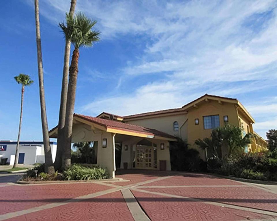 a house with palm trees in a parking lot at Quality Inn Harlingen in Harlingen