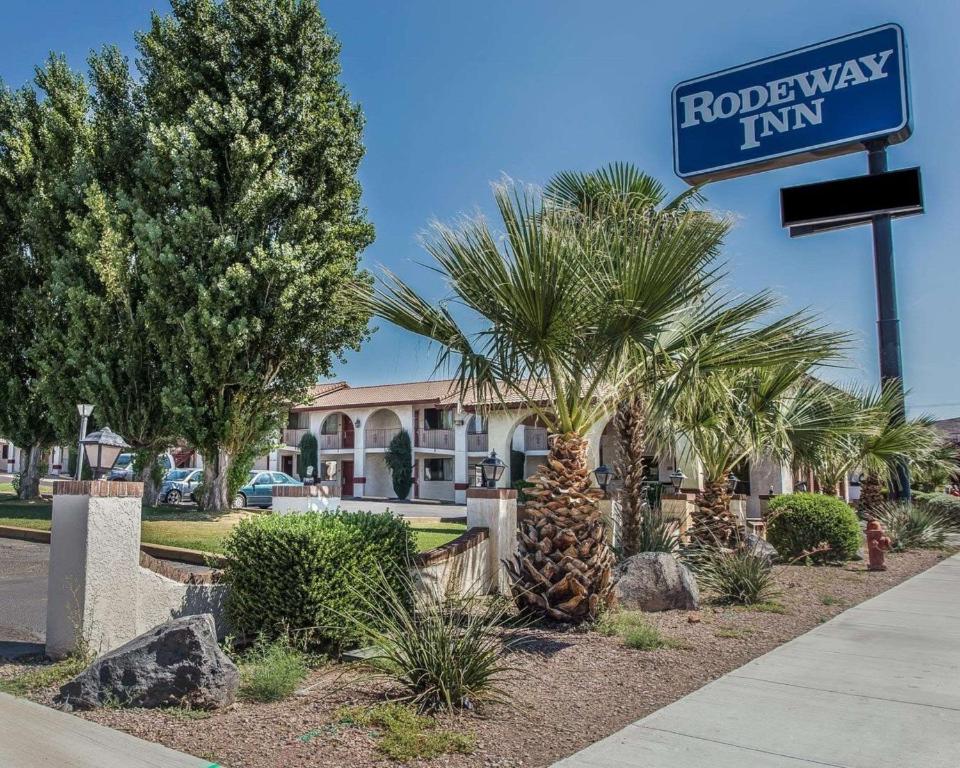 een bord voor een hotel met palmbomen en een gebouw bij Rodeway Inn Hurricane - Zion National Park Area in Hurricane