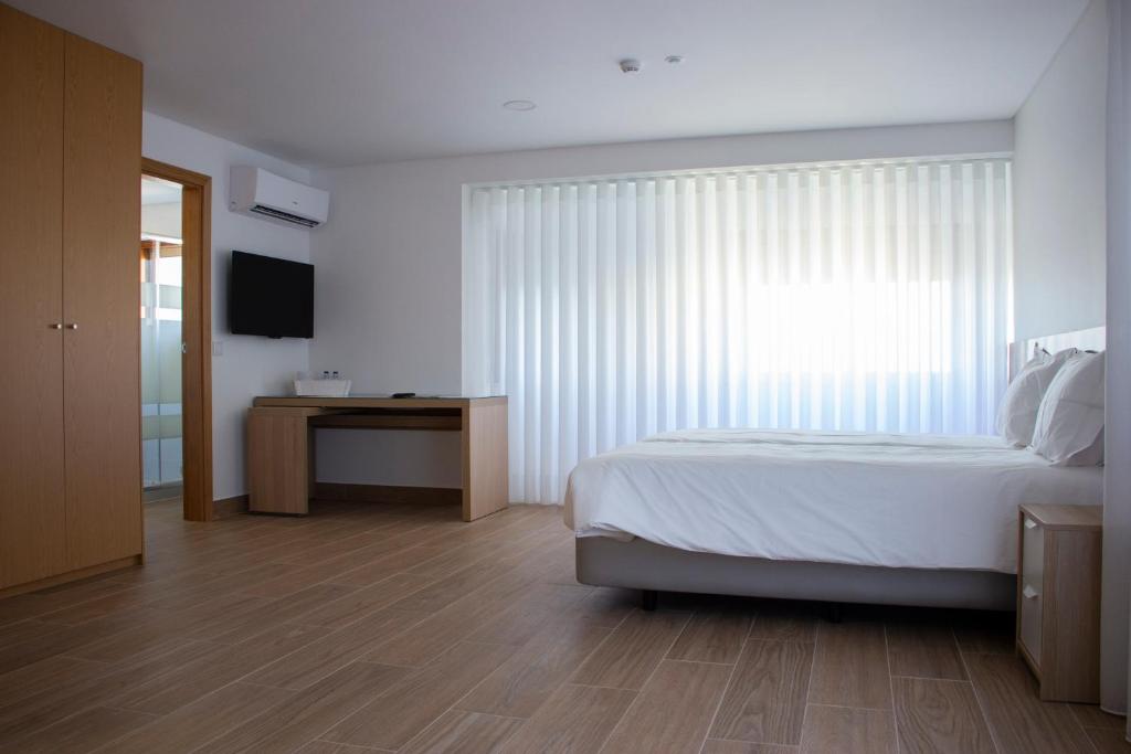 ein weißes Schlafzimmer mit einem Bett und einem TV in der Unterkunft Central Suites 3 in São João da Madeira