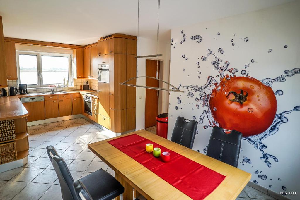 een keuken met een tafel en een grote tomaat aan de muur bij Ferienwohnung am Diersfordter Waldsee in Wesel