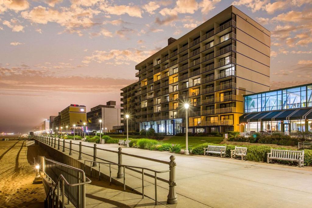 ein Gebäude mit Bänken vor einem Gebäude in der Unterkunft Coastal Hotel & Suites Virginia Beach - Oceanfront in Virginia Beach