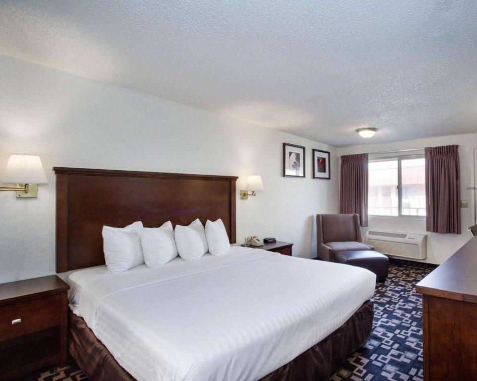 um quarto de hotel com uma cama grande e uma cadeira em MorningGlory Inn & Suites em Bellingham