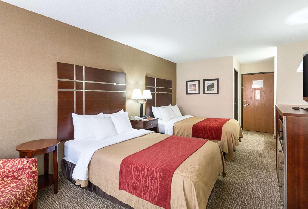 a hotel room with two beds and a chair at Quality Inn Parkersburg North-Vienna in Parkersburg