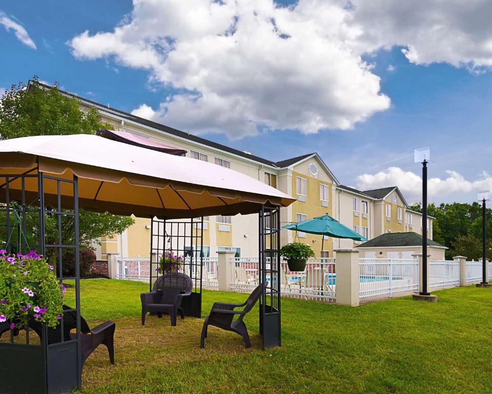 un cortile con sedie e ombrellone di fronte a un edificio di Quality Inn Spring Mills - Martinsburg North a Martinsburg