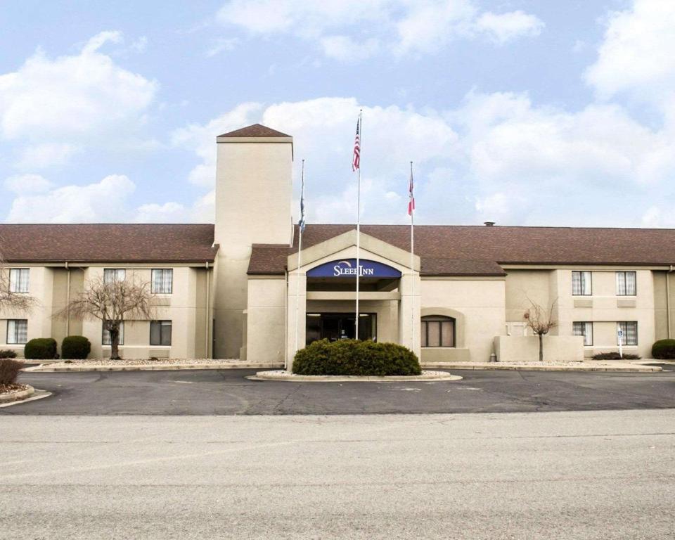 a building with two flags in a parking lot at Sleep Inn in Summersville