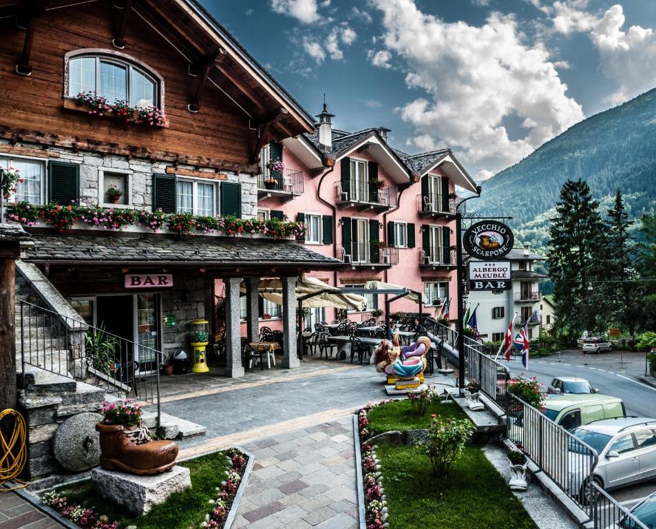 eine Frau, die auf einem Stuhl vor einem Gebäude sitzt in der Unterkunft Albergo Meublè Vecchio Scarpone in Baceno