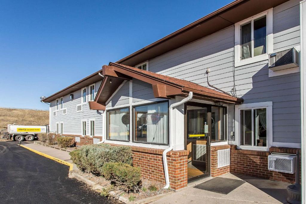 a white building with a brown roof at Rodeway Inn Cheyenne I-80 East in Cheyenne