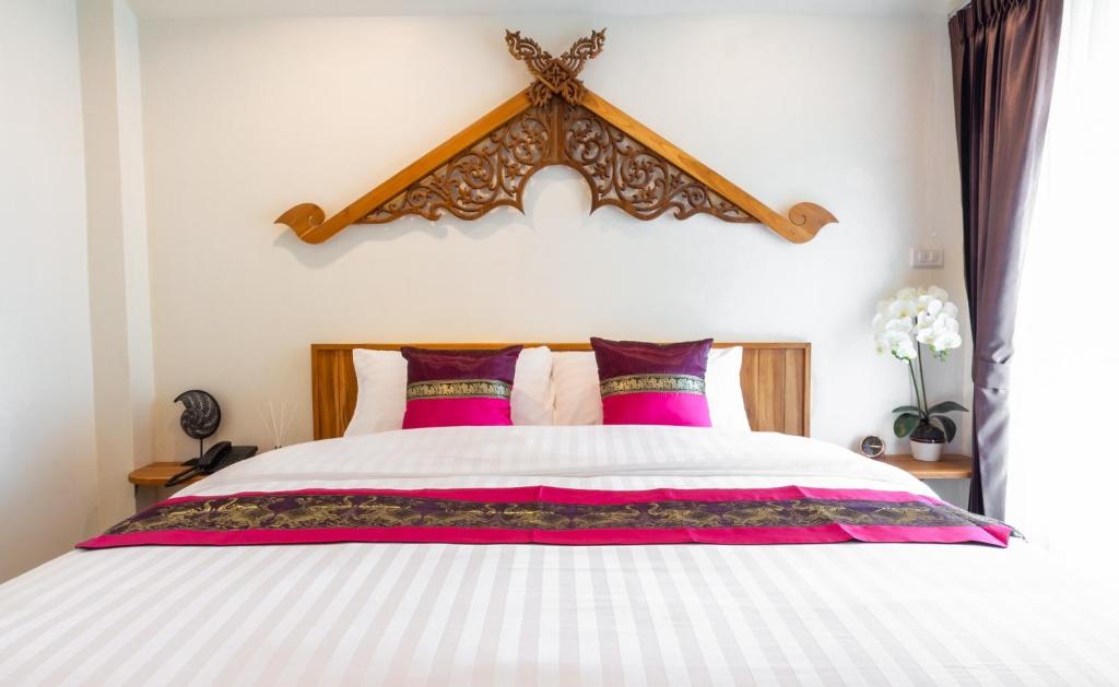 a bedroom with a large bed with pink pillows at Anumat Premium Budget Hotel in Chiang Mai
