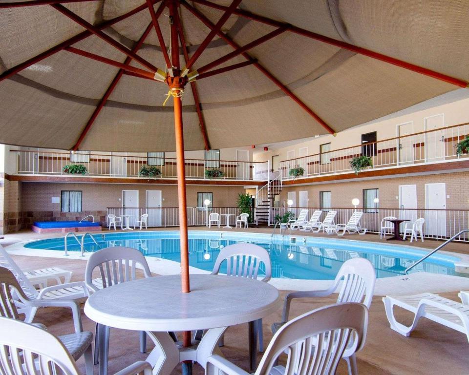 einen Pool mit einem Tisch, Stühlen und einem Sonnenschirm in der Unterkunft Knights Inn & Suites Emporia in Emporia