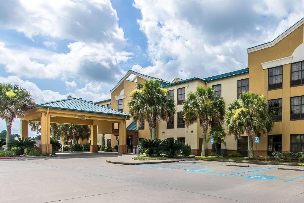 a hotel with palm trees in front of a building at Quality Suites New Iberia in New Iberia