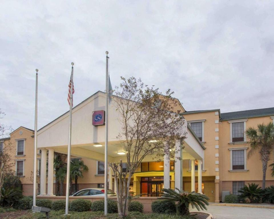a hotel with a flag in front of a building at Comfort Suites Port Allen - Baton Rouge in Port Allen