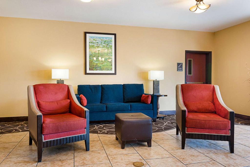 ein Wohnzimmer mit einem blauen Sofa und 2 Stühlen in der Unterkunft Quality Inn Opelousas in Opelousas