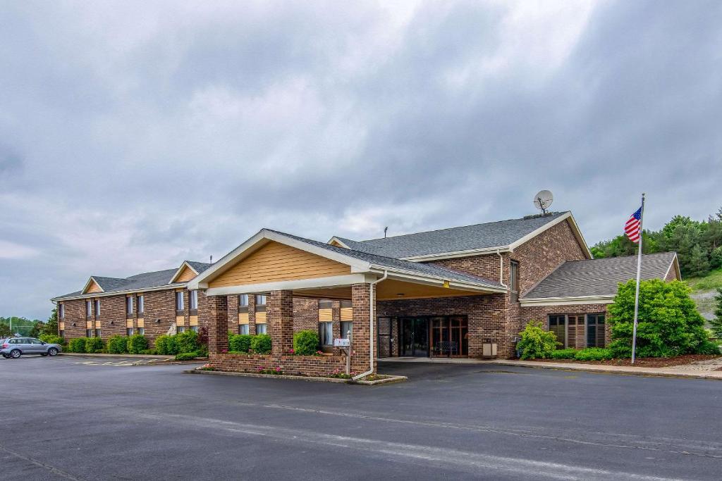 un gran edificio de ladrillo con una bandera en el aparcamiento en Quality Inn Tully I-81 en Tully