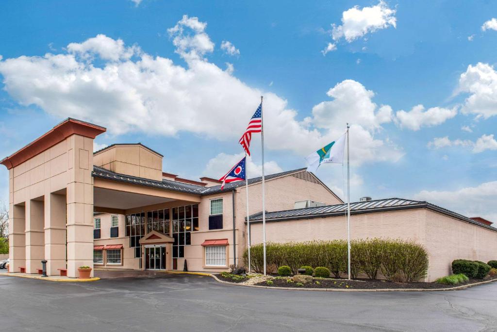 un hotel con tres banderas en un estacionamiento en Quality Hotel Conference Center Cincinnati Blue Ash en Blue Ash