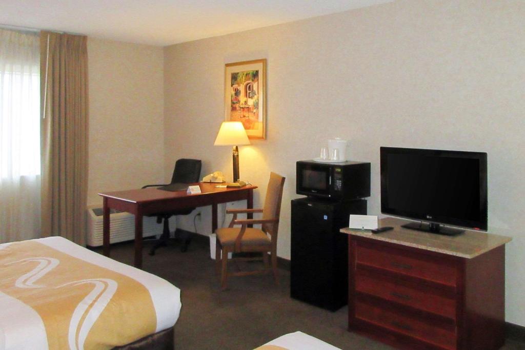 a hotel room with a bed and a desk with a television at Quality Inn & Suites Albuquerque Downtown University in Albuquerque