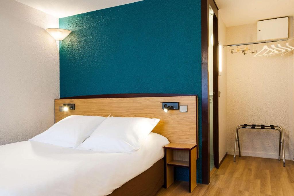 sypialnia z dużym łóżkiem z niebieską ścianą w obiekcie Comfort Hotel Lens - Noyelles Godault w mieście Noyelles-Godault