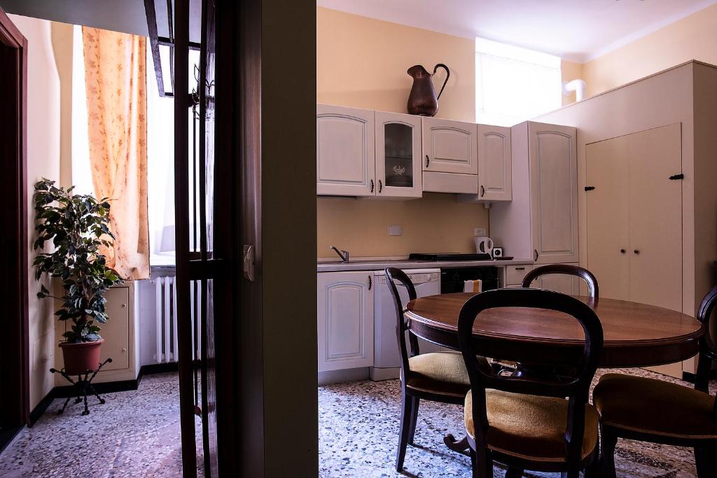 ジェノヴァにあるCasa Costa Classicaの白いキャビネット、テーブルと椅子付きのキッチンが備わります。