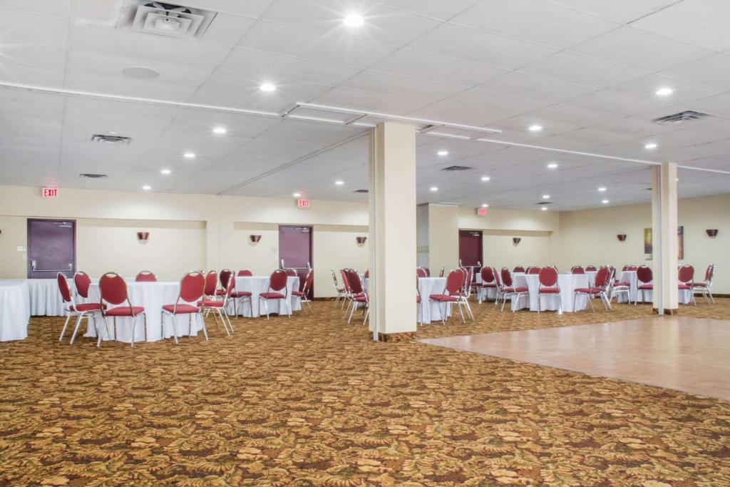 a banquet hall with white tables and red chairs at Quality Inn in Bracebridge