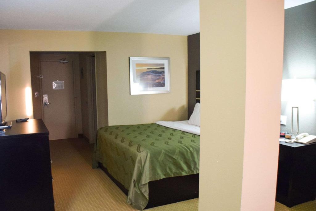 a hotel room with a bed with a green bedspread at Quality Inn in Bracebridge
