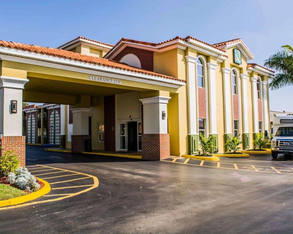 a building with a car parked in a parking lot at Quality Inn Airport - Cruise Port in Tampa