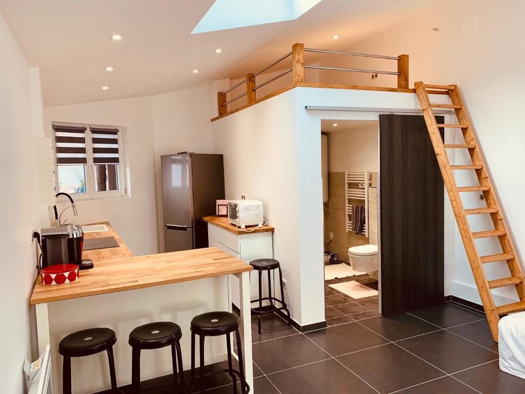 a loft bed in a kitchen with a desk and stools at Dépendance au calme dans un cadre bucolique Strasbourg Europapark in Fegersheim